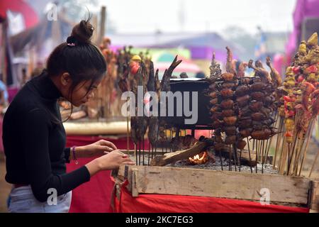 Il cibo tradizionale assamese viene preparato per la vendita in occasione della celebrazione del festival Magh Bihu nel distretto di Nagaon di Assam, in India, il 14,2021 gennaio. Magh Bihu è la festa del raccolto del nord-est dello stato di Assam ed è osservato nel mese assamese di Magh, che coincide con gennaio (Foto di Anuwar Hazarika/NurPhoto) Foto Stock