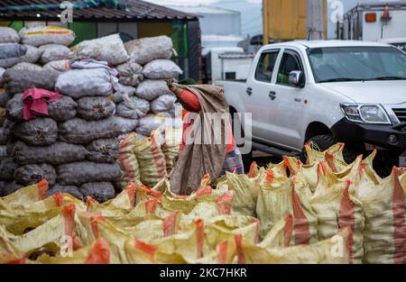 Un operaio del Quito Wholesale Market attende e guarda come una donna indigena ecuadoriana è responsabile di pesare la quantità esatta di patate nei sacchi. Il 15 gennaio 2021 a Quito, Ecuador. (Foto di Rafael Rodriguez/NurPhoto) Foto Stock