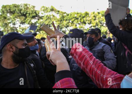 Una giovane protesta femminile solleva una pagnotta mentre fa cantare la vittoria durante una manifestazione anti-governativa svoltasi in Avenue Habib Bourguiba, nella capitale Tunisi, in Tunisia, il 19 gennaio 2021, per protestare contro il governo del primo ministro Hichem Mechichi, E a sostegno dei movimenti di protesta che hanno colpito la Tunisia in diverse città durante la notte degli ultimi giorni. I manifestanti si scontrarono con le forze di sicurezza che spararono gas lacrimogeni e usarono spray al pepe nel tentativo di disperderli. Hanno anche chiesto il rilascio di giovani arrestati dalla polizia durante le ultime proteste, e deno Foto Stock