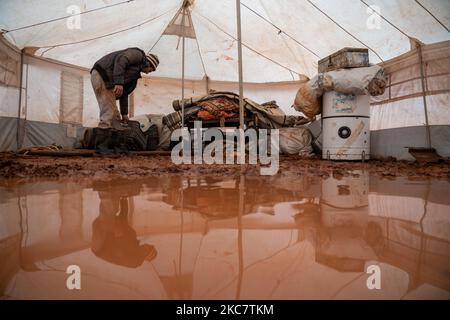 Abu Ahmed cerca di asciugare la sua tenda nel campo profughi di al-Hilal dopo che una pesante tempesta di pioggia ha portato ad un'alluvione nei campi profughi siriani a Idlib il 19 gennaio 2021 (Foto di Karam Almasri/NurPhoto) Foto Stock