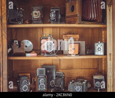 Un primo piano di una collezione di vecchie macchine fotografiche antiche su scaffali di legno Foto Stock