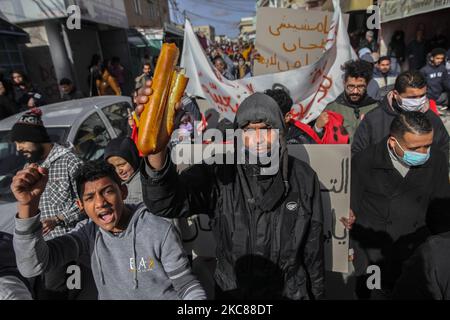 Un protettore solleva una pagnotta di pane mentre partecipava a una marcia di protesta iniziata nel quartiere popolare e duro di Hay Ettadhamen, una delle città più popolate di Tunisi, E si dirigono verso la città di Bardo a Tunisi, per protestare contro la brutalità della polizia, l'emarginazione e la crisi economica e sociale del paese. I manifestanti avevano anche chiesto il rilascio di giovani arrestati dalla polizia durante le ultime proteste notturne, dove si erano scontrati con le forze di sicurezza. Le forze di sicurezza hanno impedito loro di dimostrare davanti alla costruzione dell'Assemblea della R. Foto Stock