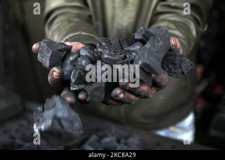 Un lavoratore palestinese raccoglie carbone da confezionare in sacchi da vendere a Jabaliya, nella striscia di Gaza settentrionale, il 28 gennaio 2021. (Foto di Majdi Fathi/NurPhoto) Foto Stock