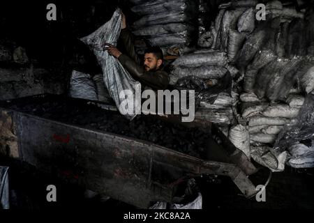 Un lavoratore palestinese raccoglie carbone da confezionare in sacchi da vendere a Jabaliya, nella striscia di Gaza settentrionale, il 28 gennaio 2021. (Foto di Majdi Fathi/NurPhoto) Foto Stock