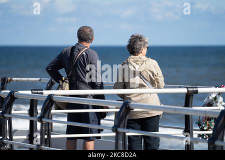 Una vista sul retro di una coppia anziana che si gode una passeggiata lungo il molo di Saltburn, Regno Unito Foto Stock