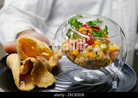 ceviche di pesce o tartare in una ciotola di vetro con cracker in una mano Foto Stock