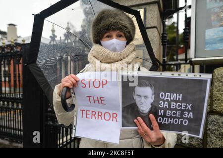 Un manifestante che indossa una maschera facciale contiene i manifesti "uno per tutti, tutti per uno" e "Stop al terrore" durante un raduno simbolico a sostegno del leader dell'opposizione russo imprigionato Alexei Navalny di fronte all'ambasciata russa a Dublino. Domenica 31 gennaio 2021 a Dublino, Irlanda. (Foto di Artur Widak/NurPhoto) Foto Stock