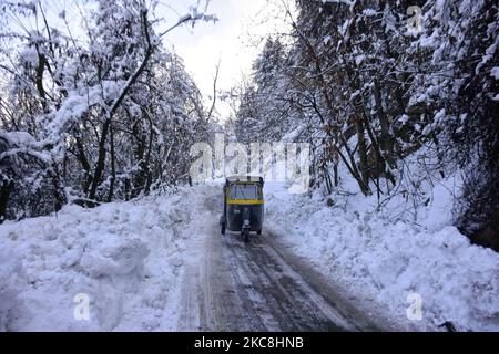 Un rickshaw auto veli su una strada coperta di neve sulle colline a piedi delle montagne di Zabarwan afte il fresco incantesimo di neve a Srinagar, indiano amministrato Kashmir on01 febbraio 2021. (Foto di Muzamil Mattoo/NurPhoto) Foto Stock