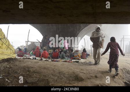 I bambini svantaggiati studiano in un'aula improvvisata allestita sotto la costruzione di un ponte in una mattina invernale nebbiosa, il 16 gennaio 2021 a Nuova Delhi, India. La libera Scuola sotto il ponte è una scuola privata a Delhi, India. Fornisce lezioni gratuite ai bambini svantaggiati. Gli studenti provengono dalle baraccopoli situate accanto al fiume Yamuna. Molti bambini svantaggiati non sono in grado di permettersi i computer portatili o tablet necessari per le lezioni online, lasciandoli senza accesso all'istruzione, mentre la pandemia del Covid-19 impera in tutta l'India. La scuola improvvisata, istituita da Foto Stock