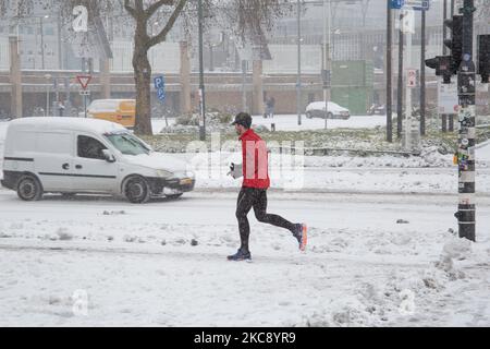 Un uomo che corre sulla neve. Blizzard dalla tempesta di neve Darcy nei Paesi Bassi, la prima nevicata pesante con forti venti intensi dopo 2010 che ha interrotto il trasporto in tutto il paese. I olandesi si svegliarono la domenica con uno strato di neve che copriva tutto. Molti incidenti si sono verificati sulle strade a causa della tempesta e delle condizioni ghiacciate, mentre c'era un problema anche con i treni. Nella città di Eindhoven, nel Brabante settentrionale, i servizi ferroviari e di autobus cessarono di funzionare, l'aeroporto seguì e il traffico aereo fu deviato. La gente è andata fuori nel centro della città di Eindhoven per divertirsi con il Foto Stock