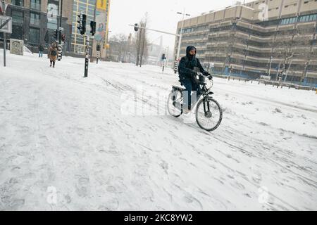 Si vedono le persone in bicicletta sulla neve nel centro di Eindhoven, coperto di neve, nel 18 Settemberplein. Blizzard dalla tempesta di neve Darcy nei Paesi Bassi, la prima nevicata pesante con forti venti intensi dopo 2010 che ha interrotto il trasporto in tutto il paese. I olandesi si svegliarono la domenica con uno strato di neve che copriva tutto. Molti incidenti si sono verificati sulle strade a causa della tempesta e delle condizioni ghiacciate, mentre c'era un problema anche con i treni. Nella città di Eindhoven, nel Brabante settentrionale, i servizi ferroviari e di autobus cessarono di funzionare, l'aeroporto seguì e il traffico aereo fu deviato Foto Stock