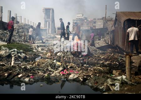 La gente si muove mentre il fuoco di immondizia genera il fumo tossico in un'area a basso reddito sul bordo esterno di Dhaka, Bangladesh lunedì 08 febbraio 2021. Secondo uno studio, l'inquinamento atmosferico riduce di 7 anni l'aspettativa di vita. (Foto di Syed Mahamudur Rahman/NurPhoto) Foto Stock