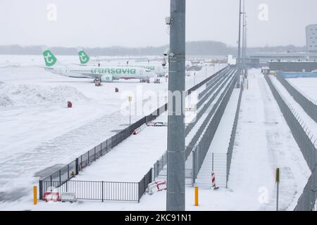 Vista generale dell'aeroporto di Eindhoven e degli aeroplani a terra del Boeing 737 di Transavia, la tempesta di neve chiude l'aeroporto di Eindhoven ein nei Paesi Bassi. La forte caduta di neve interrompe il traffico aereo che ha causato deviazioni verso la Germania la domenica. Blizzard dalla tempesta Darcy ha colpito il paese da Domenica mattina (07.02.2021) con conseguenti problemi di trasporto pubblico. Nell'aeroporto di Eindhoven, innevato, gli aeroplani di Transavia sono visti a terra mentre i macchinari pesanti stanno pulendo la pista e la tassamia. Decine di voli che dovevano partire sono stati ritardati o cancellati all'aeroporto Schiphol di Amsterdam a causa di t Foto Stock