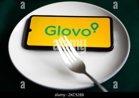 Il logo dell'app Glovo viene visualizzato sullo schermo di un telefono cellulare fotografato per l'illustrazione su un piatto e con posate. Cracovia, Polonia il 9 febbraio 2021. I numeri mostrano che la pandemia di Covid-19 ha determinato un aumento significativo dei pasti ordinati online attraverso le app e i siti web per la consegna dei prodotti alimentari. (Foto di Beata Zawrzel/NurPhoto) Foto Stock