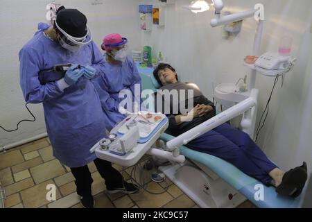 Angélica Martínez e Ayax Malacate, chirurghi dentistici, assistono ad un paziente che ha assistito ad effettuare le prove dentali della protesi durante l'emergenza sanitaria ed il semaforo epidemiologico arancione, alla loro clinica situata a Colonia Las Arboledas Tláhuac, Città del Messico. Prima dell'inizio della vaccinazione contro il COVID-19 in Messico, l'Unione dentale ha lanciato una campagna per rendere visibile la necessità di essere considerati nella prima fase del piano nazionale di vaccinazione, poiché nella loro pratica professionale quotidiana sono a rischio di essere infettati con coronavirus da essere in contatto diretto con la bocca e saliva Foto Stock