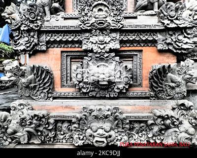 Una foto di demoni balinesi o mostri e fiori scultura in pietra incisa su una parete del lato del tempio a Ubud, sull'isola di Bali, Indonesia Foto Stock