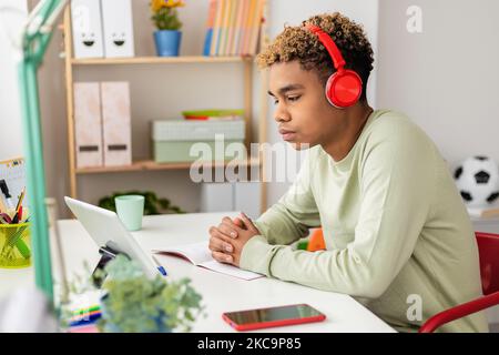 Concentrato giovane ispanico latino uomo imparare la lingua guardando corso online Foto Stock