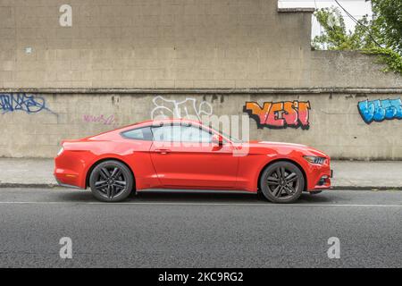 A red Ford Mustang parked in south Dublin, Ireland against a wall of graffiti Stock Photo