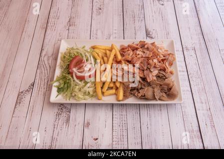 Vassoio tipico di un ristorante kebab con carne mista di pollo e agnello, patatine fritte e insalata con pomodoro e cipolla Foto Stock