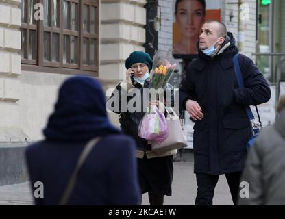 Una donna Ucraina che indossa una maschera facciale cammina con fiori lungo una strada a Kiev, Ucraina il 06 marzo 2021. La Giornata internazionale della donna si celebra in Europa orientale e in alcuni paesi il 08 marzo e le persone che celebrano tradizionalmente acquistano fiori per le donne in questo giorno o pochi giorni prima. In alcuni luoghi, è un giorno di protesta per i diritti delle donne in altri, è un giorno che celebra la donna. (Foto di Str/NurPhoto) Foto Stock