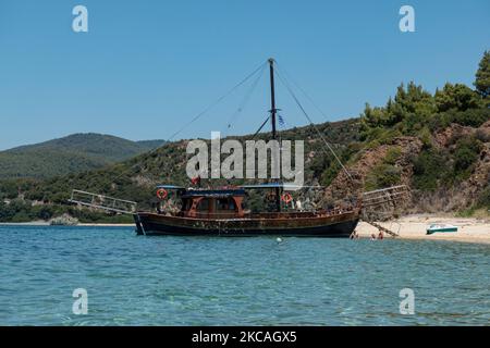 Navi pirata che trasportano turisti dall'altra parte della penisola. Aretes spiaggia nella zona di Toroni a Halkidiki. La spiaggia con la sabbia dorata e l'acqua cristallina smeraldo, tipica del Mar Egeo e del Mediterraneo, è composta da 3 diverse baie. La costa protetta da colline rocciose intorno è un tesoro nascosto per la gente del posto e i turisti senza le scene d'estate sovraffollate con i bar sulla spiaggia. Il CHALKIDIKI è una meta turistica molto popolare, famosa per le migliori spiagge del paese, a breve distanza in auto, vicino alla città di Salonicco. La Grecia sta spingendo per una vaccinazione COVID Foto Stock