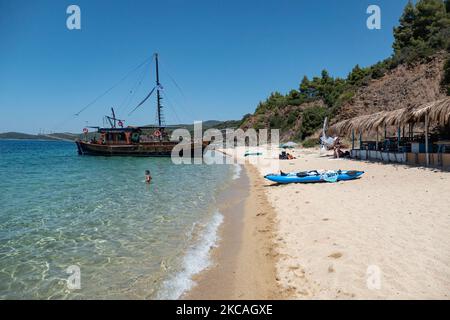 Navi pirata che trasportano turisti dall'altra parte della penisola. Aretes spiaggia nella zona di Toroni a Halkidiki. La spiaggia con la sabbia dorata e l'acqua cristallina smeraldo, tipica del Mar Egeo e del Mediterraneo, è composta da 3 diverse baie. La costa protetta da colline rocciose intorno è un tesoro nascosto per la gente del posto e i turisti senza le scene d'estate sovraffollate con i bar sulla spiaggia. Il CHALKIDIKI è una meta turistica molto popolare, famosa per le migliori spiagge del paese, a breve distanza in auto, vicino alla città di Salonicco. La Grecia sta spingendo per una vaccinazione COVID Foto Stock