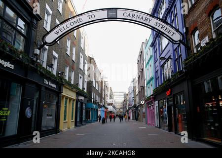 La gente passa accanto a negozi temporaneamente chiusi in una vicina Carnaby Street a Londra, Inghilterra, il 8 marzo 2021. Oggi ha segnato la prima fase dell’allentamento del blocco del coronavirus in tutta l’Inghilterra, con la riapertura delle scuole e l’allentamento di alcuni limiti sui contatti sociali. I negozi non essenziali, i bar, i ristoranti e le altre aziende di ospitalità rimangono comunque chiusi e riapriranno solo il mese prossimo secondo gli orari attuali. (Foto di David Cliff/NurPhoto) Foto Stock