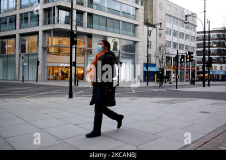 Una donna che indossa una maschera facciale cammina lungo una Oxford Street quasi deserta a Londra, Inghilterra, il 11 marzo 2021. Questa settimana ha segnato la prima fase del lockdown easing del coronavirus in tutta l’Inghilterra, con la riapertura delle scuole e l’allentamento di alcuni limiti sui contatti sociali. I negozi non essenziali, i bar, i ristoranti e le altre aziende del settore alberghiero e del tempo libero rimangono tuttavia chiusi e riapriranno solo il mese prossimo secondo gli orari attuali. (Foto di David Cliff/NurPhoto) Foto Stock