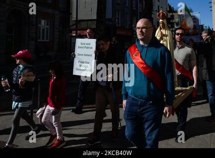 Un uomo porta un cartello che recita: "Dio un San Patrizio Salva l'Irlanda dal nostro governo malvagio!" Come molte persone prendono parte a una processione religiosa attraverso il centro di Dublino, con i fedeli che portano una statua di nostra Signora di Fatima, il giorno di San Patrizio, durante il blocco del livello 5 Covid-19. Mercoledì 17 marzo 2021 a Dublino, Irlanda. (Foto di Artur Widak/NurPhoto) Foto Stock