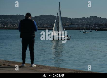 Un uomo guarda i marinai che praticano nel porto di Dún Laoghaire, vicino al Molo Ovest, durante il blocco del livello 5 Covid-19. Domenica 21 marzo 2021 a Dublino, Irlanda. (Foto di Artur Widak/NurPhoto) Foto Stock