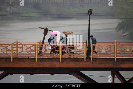 La gente attraversa il ponte pedonale mentre le piogge lasca Srinagar, Kashmir il 22 marzo 2021. Il reparto meteorologico aveva previsto l'incantesimo bagnato attraverso Jammu e Kashmir con la maggiore intensità di previsione prevista il 22nd e 23rd marzo. (Foto di Faisal Khan/NurPhoto) Foto Stock