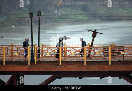 La gente attraversa il ponte pedonale mentre le piogge lasca Srinagar, Kashmir il 22 marzo 2021. Il reparto meteorologico aveva previsto l'incantesimo bagnato attraverso Jammu e Kashmir con la maggiore intensità di previsione prevista il 22nd e 23rd marzo. (Foto di Faisal Khan/NurPhoto) Foto Stock