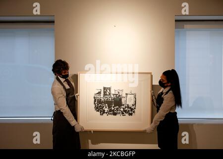 I gestori d'arte posano tenere 'morons (White)', dell'artista britannico Banksy, stimato a GBP40.000-60.000, durante un'anteprima alla casa d'aste di Christie a Londra, in Inghilterra, il 26 marzo 2021. (Foto di David Cliff/NurPhoto) Foto Stock