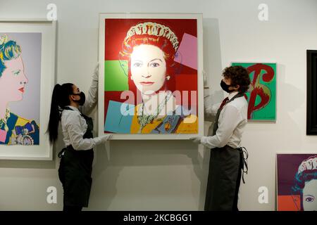 I gestori d'arte si pongono tenendo la "Regina Elisabetta II, da: Regnanti Regine (Edizione reale)" (R), dell'artista americano Andy Warhol, stimata tra il GBP100.000 e il 150.000, e tra una delle quattro serie di Warhol "Regina Margarethe II di Danimarca, da: Regning Queens (Royal Edition)' (L), stimato a GBP60.000-80.000, e '($)1' (R) di Warhol, stimato a GBP40.000-60.000, durante un'anteprima alla casa d'aste di Christie a Londra, Inghilterra, il 26 marzo 2021. (Foto di David Cliff/NurPhoto) Foto Stock