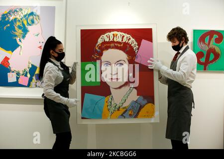 I gestori d'arte si pongono tenendo la "Regina Elisabetta II, da: Regnanti Regine (Edizione reale)" (R), dell'artista americano Andy Warhol, stimata tra il GBP100.000 e il 150.000, e tra una delle quattro serie di Warhol "Regina Margarethe II di Danimarca, da: Regning Queens (Royal Edition)' (L), stimato a GBP60.000-80.000, e '($)1' (R) di Warhol, stimato a GBP40.000-60.000, durante un'anteprima alla casa d'aste di Christie a Londra, Inghilterra, il 26 marzo 2021. (Foto di David Cliff/NurPhoto) Foto Stock