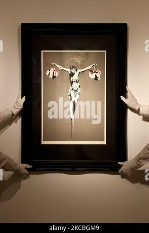 I gestori dell'arte posano tenere "Christ with Shopping", dell'artista britannico Banksy, stimato tra il GBP100.000 e il 150.000, durante un'anteprima alla casa d'aste Christie's a Londra, Inghilterra, il 26 marzo 2021. (Foto di David Cliff/NurPhoto) Foto Stock