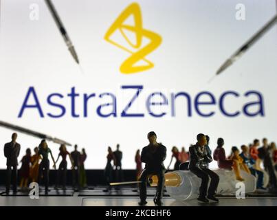 Siringhe mediche e piccole figurine di persone sono visibili davanti al logo AstraZeneca visualizzato su uno schermo. Sabato 26 marzo 2021 a Dublino, Irlanda. (Foto di Artur Widak/NurPhoto) Foto Stock