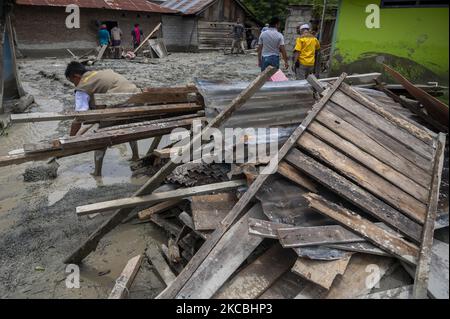 Residenti e volontari hanno ripulito il fango rimasto che ha colpito le case nel villaggio di Beka, nel distretto di Marawola, nella reggenza di Sigi, nella provincia di Sulawesi centrale, in Indonesia il 27 marzo 2021. L'alluvione di fango che si è verificata il 26 marzo 2021 quella notte è stata causata da forti piogge che hanno causato frane in montagna e spazzato via. Insediamenti in quella regione. Non ci sono state vittime nell'incidente, ma almeno 70 case sono state gravemente danneggiate, più di 100 case sono state leggermente danneggiate e inondate da fango, e circa 200 residenti hanno dovuto essere evacuati. (Foto di Basri Marzuki/NurPhoto) Foto Stock