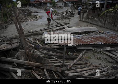 Residenti e volontari hanno ripulito il fango rimasto che ha colpito le case nel villaggio di Beka, nel distretto di Marawola, nella reggenza di Sigi, nella provincia di Sulawesi centrale, in Indonesia il 27 marzo 2021. L'alluvione di fango che si è verificata il 26 marzo 2021 quella notte è stata causata da forti piogge che hanno causato frane in montagna e spazzato via. Insediamenti in quella regione. Non ci sono state vittime nell'incidente, ma almeno 70 case sono state gravemente danneggiate, più di 100 case sono state leggermente danneggiate e inondate da fango, e circa 200 residenti hanno dovuto essere evacuati. (Foto di Basri Marzuki/NurPhoto) Foto Stock