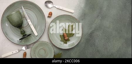 Beautiful plates with cutlery, glass and acorns on grunge background with space for text Stock Photo