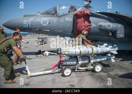 I Marines trasportano bombe GBU-54 sul ponte di volo dell'isola USS Makin. Foto Stock