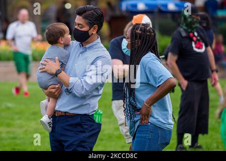 Aftab Pureval, l'Hamilton County Clerk of Courts, tiene un bambino mentre la gente si riunisce a Washington Park in memoria e poi marzo a dove Timothy Thomas è morto 20 anni fa questo mese dopo essere stato ucciso e ucciso da un poliziotto di Cincinnati, Stephen Roach, Che alla fine ha portato a disordini civili in tutta la città, mercoledì 7 aprile 2021, a Cincinnati, Ohio, Stati Uniti. (Foto di Jason Whitman/NurPhoto) Foto Stock