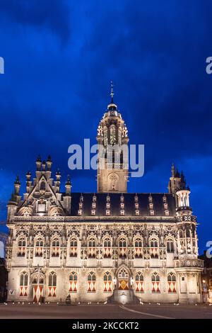 Illuminato dall'iconico Municipio di Middelburg, una delle principali attrazioni monumentali della città, un punto di riferimento architettonico visto dopo il tramonto durante l'ora magica del tramonto con nuvole scure nel cielo. Lo Stadhuis è un edificio del 15-16th secolo con uno stile architettonico gotico, uno dei più raffinati del paese. Gli interni sono bruciati interamente nel maggio 1940 durante i bombardamenti della seconda guerra mondiale. Proprio ora l'edificio è in uso presso l'università. Middelburg è la capitale della provincia olandese della Zeeland, una famosa e popolare destinazione turistica per la gente del posto e tra internazionali Foto Stock