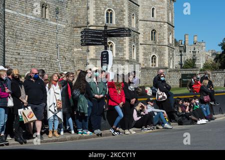 WINDSOR, REGNO UNITO - 17 APRILE 2021: La gente osserva un minuto di silenzio fuori dal Castello di Windsor il giorno dei funerali del principe Filippo, il marito della regina Elisabetta II, morto la settimana scorsa a 99 anni, il 17 aprile 2021 a Windsor, Inghilterra. Il funerale cerimoniale del Duca di Edimburgo si svolge interamente all'interno dei terreni del Castello di Windsor e al pubblico è stato chiesto di non riunirsi lì o in altre residenze reali a causa delle restrizioni di blocco del Covid-19. (Foto di Wiktor Szymanowicz/NurPhoto) Foto Stock