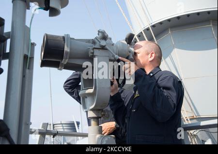 Il comandante della Marina statunitense guarda attraverso i grandi occhi a bordo della USS Carney. Foto Stock