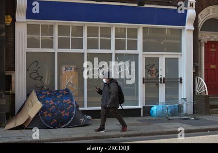 Un uomo che indossa una maschera facciale passa davanti a una tenda con un letto ruvido fuori dall'ingresso di un edificio chiuso nel centro di Dublino, durante il blocco COVID-19. Sabato, 17 aprile 2021, a Dublino, Irlanda. (Foto di Artur Widak/NurPhoto) Foto Stock