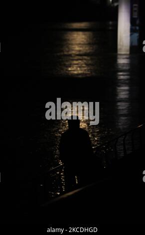 Una silhouette di una persona viene vista contro la luce riflessa nel fiume Vistola a Varsavia, Polonia, il 27 aprile 2021. La Super Luna Rosa è seconda all'ultima super lune nel 2021. (Foto di Str/NurPhoto) Foto Stock