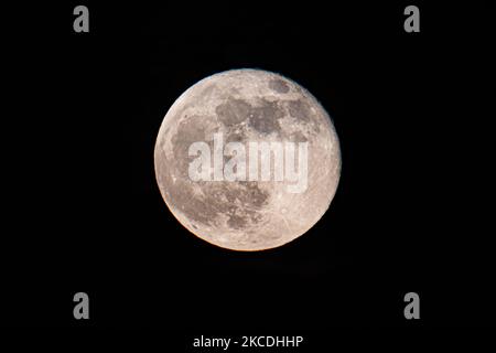 La Luna piena o la Superluna Rosa o la Luna Super Rosa del 2021 aprile, come si vede dalla città olandese, Eindhoven, Paesi Bassi il 27 aprile 2021, che si erge sopra l'orizzonte dietro gli edifici di colore rosso. La luna piena super è più grande e più luminosa nel cielo perché è più vicina alla Terra., 14 per cento più grande e 30 per cento più luminoso di una dimensione e luminosità comuni di una luna normale. Il nome della Luna Rosa è legato alla fioritura primaverile dei fiori. Altri nomi il satellite naturale della Terra in orbita attorno al pianeta e il satellite più grande del sistema solare sono Selene, Luna e Cynthia. (Pho Foto Stock