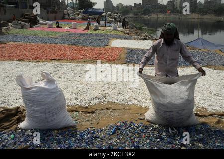 Un lavoratore sparge trucioli di plastica riciclata dopo il lavaggio nel fiume Buriganga a Dhaka, Bangladesh il 05 maggio 2021. Il fiume Buriganga, che scorre dalla città di Dhaka, è oggi uno dei fiumi più inquinati del mondo a causa del dilagante dumping di sprechi umani e industriali. (Foto di Syed Mahamudur Rahman/NurPhoto) Foto Stock