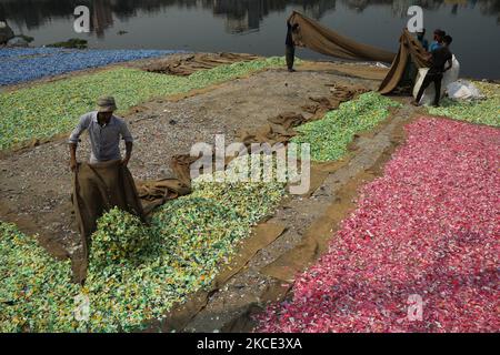 Gli operai spargono i trucioli di plastica riciclati dopo il lavaggio nel fiume Buriganga a Dhaka, Bangladesh il 05 maggio 2021. Il fiume Buriganga, che scorre dalla città di Dhaka, è oggi uno dei fiumi più inquinati del mondo a causa del dilagante dumping di sprechi umani e industriali. (Foto di Syed Mahamudur Rahman/NurPhoto) Foto Stock